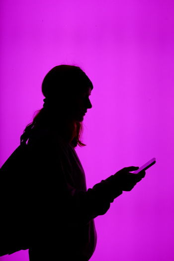 Side view of silhouette woman using mobile phone