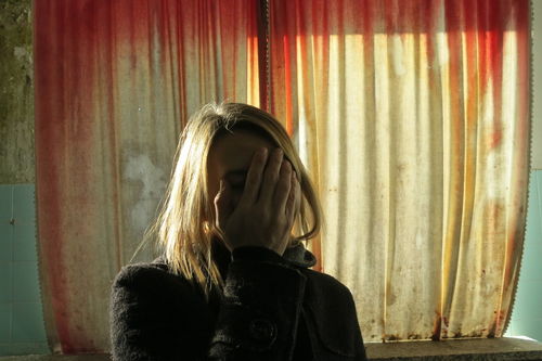 Woman covering face against curtain