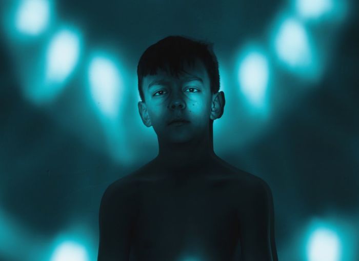 Close-up portrait of boy against illuminated lights