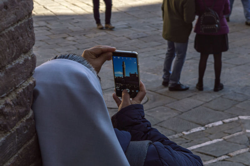 Rear view of nun photographing palazzo pubblico through smartphone