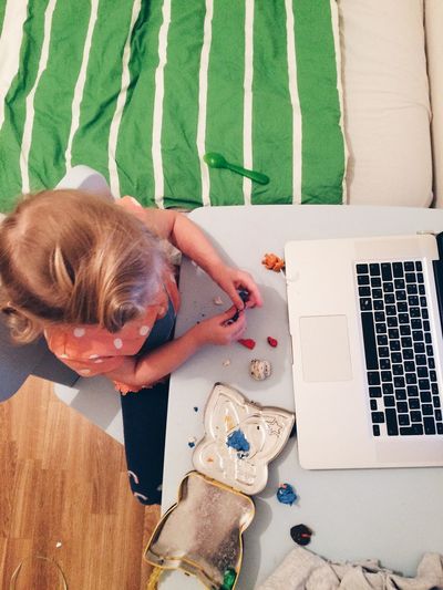 High angle view of girl playing with clay while sitting in front of laptop at home