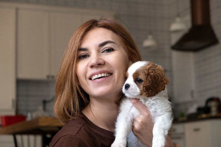 Cavalier king charles spaniel blenheim. close up portrait of cute dog puppy with woman hostess