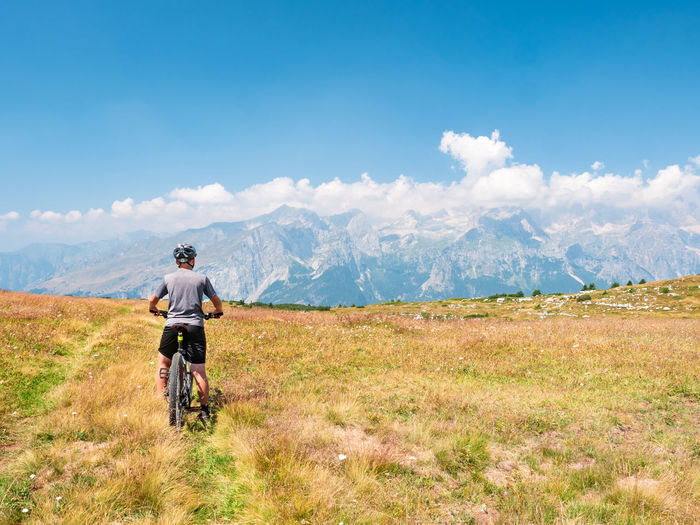 Young boy stop ridding bike on peak trek and enjoy alps peak overview.  north italy alps in summer 