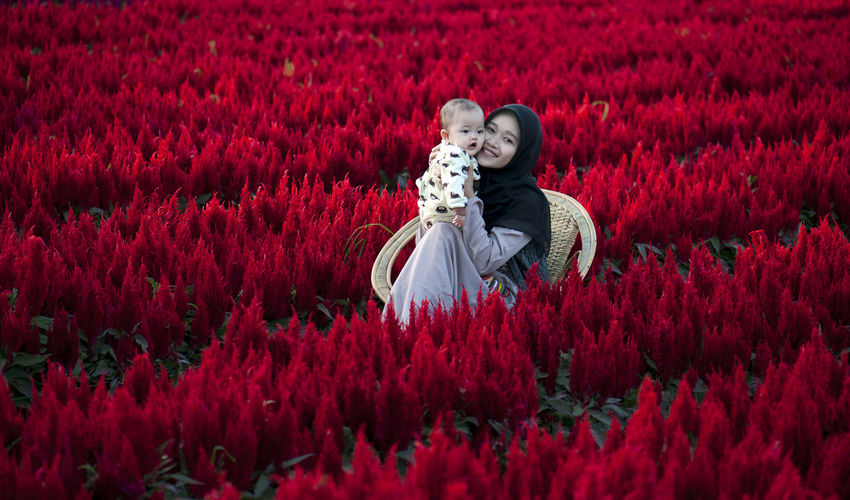 Young couple on red flowering plants on field