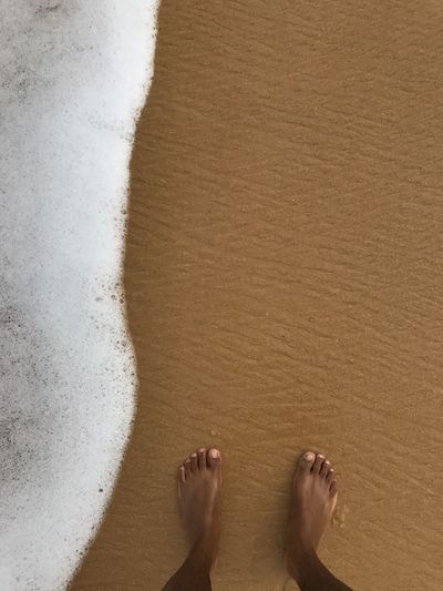 Low section of man feet standing on sea shore in trancoso brazil 