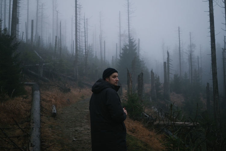 Man standing in forest during foggy weather
