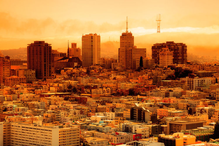 Aerial view of buildings in city against sky during sunset