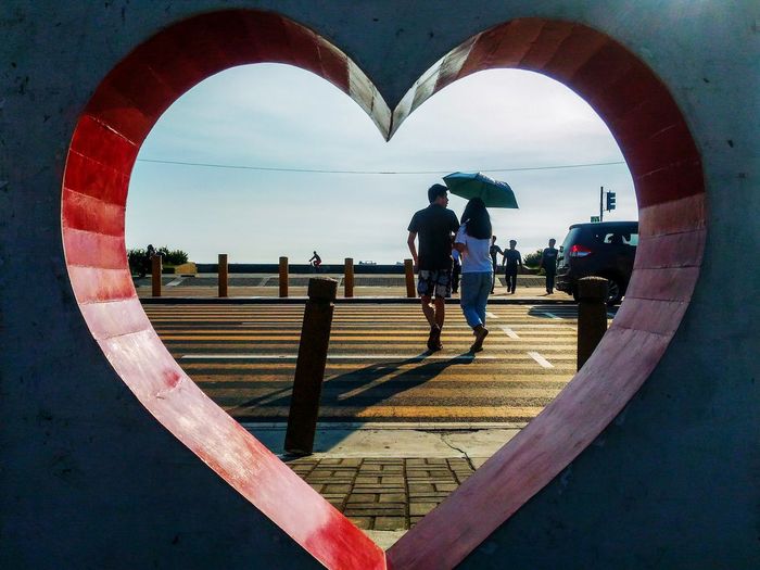 Couple crossing the pedestrian while framed by a heart.