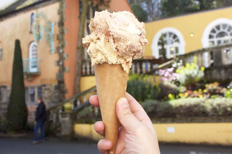 Hand holding ice cream cone outdoors