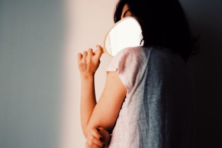 Rear view of woman holding hands against wall