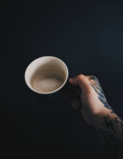Man holding coffee cup against black background