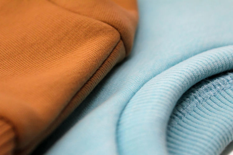 Two sweatshirts of blue and ochre color are close-up.