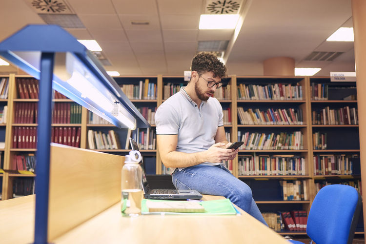 Portrait of a brown boy using a mobile phone in a library