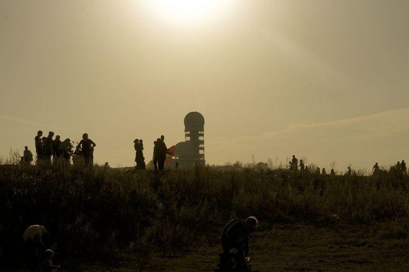 Silhouette people enjoying at teufelsberg against sky during sunset