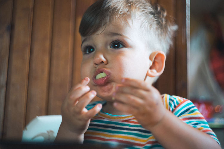 Close-up of boy eating cucumber at home