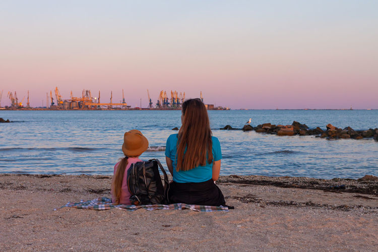 Girl staycation picnicking on sea beach  amazing colorful sunset.trend local travel.evening seascape