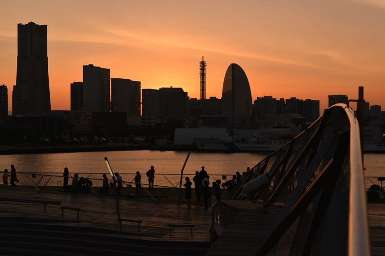 People at osanbashi pier against sky during sunset