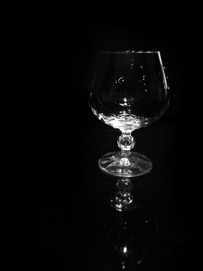 Close-up of wineglass on table against black background