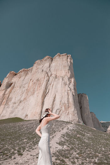 Low section of woman standing on rock against sky