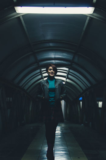 Full length portrait of woman standing in illuminated tunnel