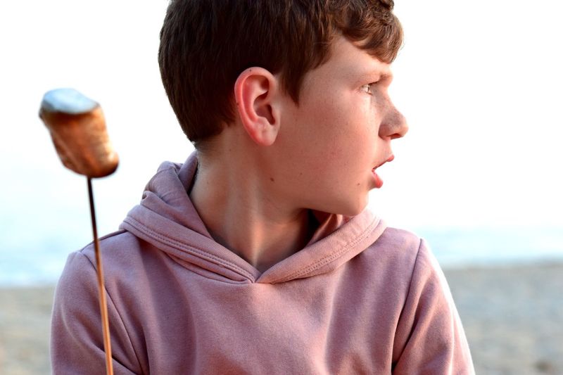 Close-up of boy looking away while roasting marshmallow