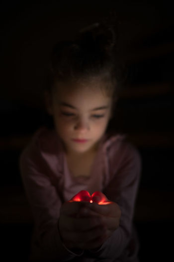 Close-up of girl holding illuminated string lights at home