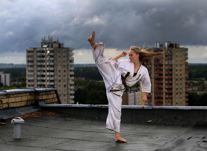 Woman doing karate on rooftop in city