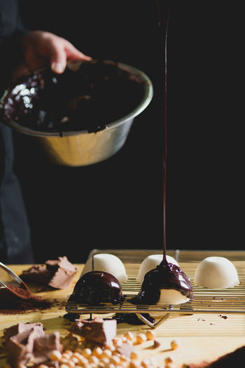 Close-up of chef dripping chocolate onto dessert