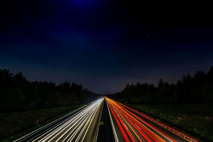 High angle view of light trails on highway against sky at night
