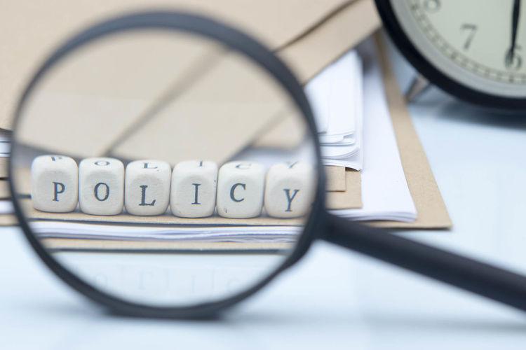 Policy text made of toy blocks with files and magnifying glass on white background