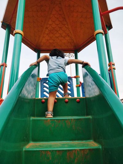Rear view of boy playing on outdoor play equipment
