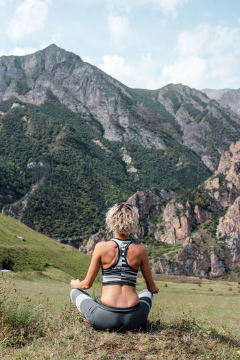 Full length rear view of woman exercising on mountain