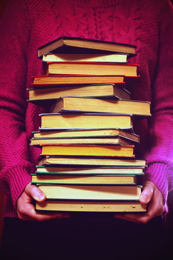 Midsection of woman holding stacked books