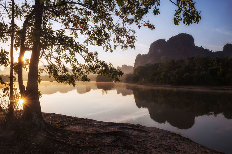 Scenic view of lake and limestone mountain formation against sky during sunrise