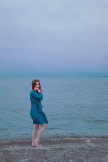 Young girl on a background of the sea in a blue dress, portrait