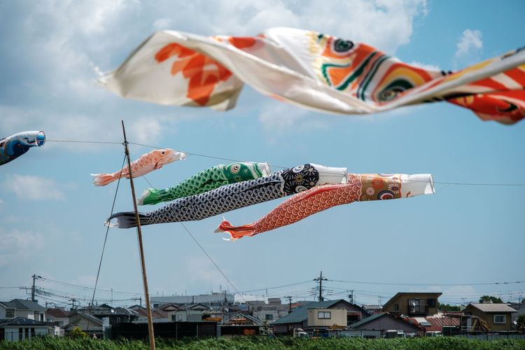 Low angle view of fish flags hanging against sky