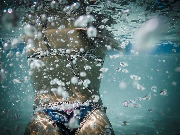 Midsection of young woman swimming undersea