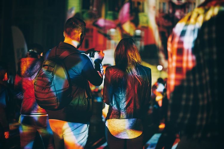 Rear view of couple standing on street at night