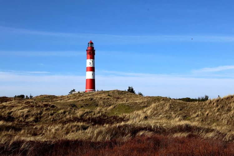 Lighthouse on landscape against blue sky