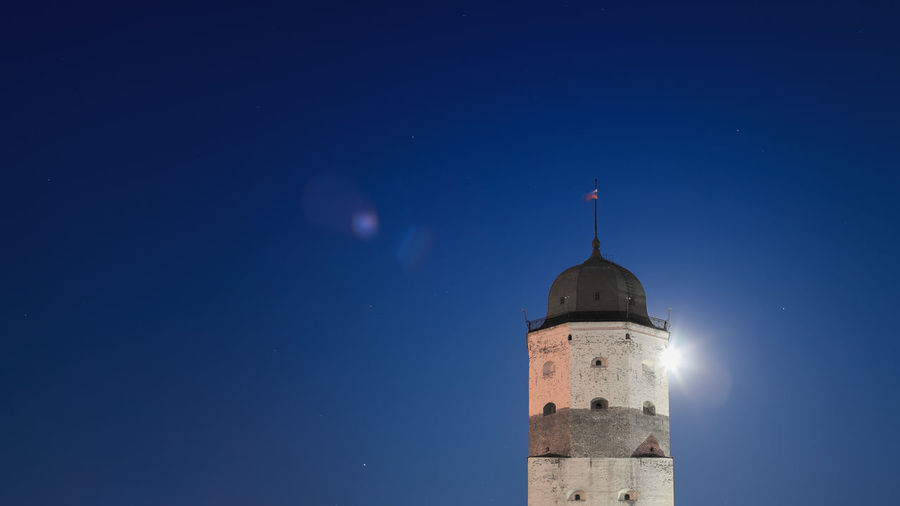 Low angle view of illuminated lighthouse against clear sky at night
