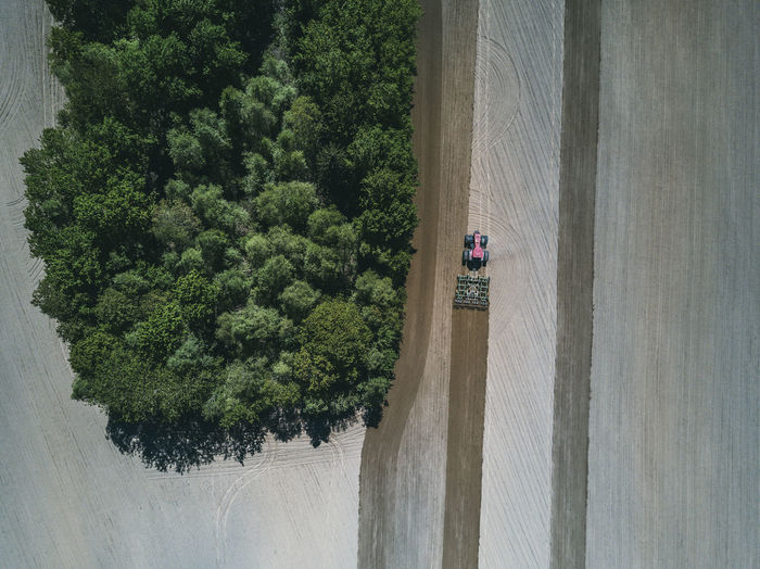 Aerial view of tractor in agricultural field by trees