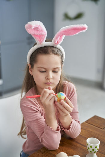 Girl painting easter egg at home