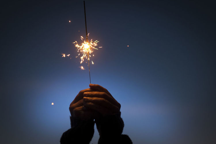 Person holding sparkler at night