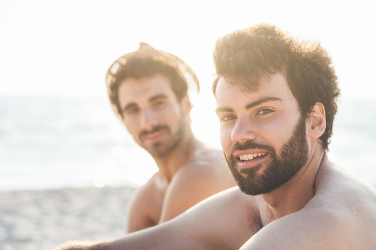 Portrait of handsome young men sitting at beach