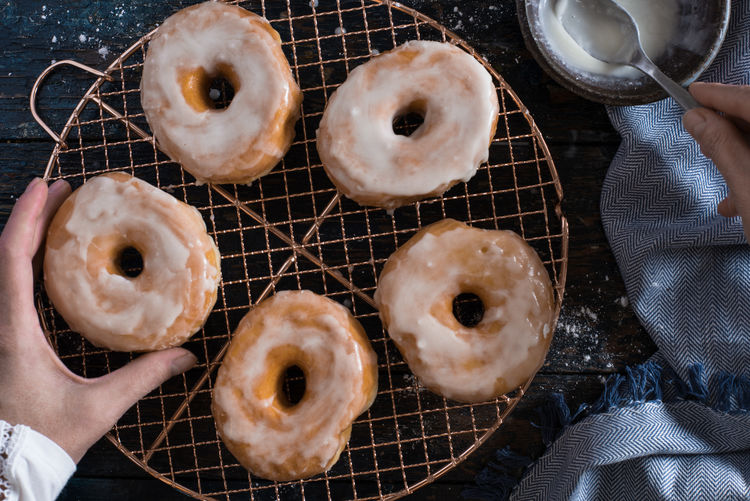 Cropped hands preparing donut on table