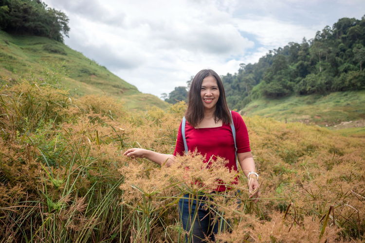 Portrait of smiling woman standing amidst plants on land