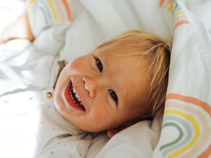 Portrait of cute boy lying on bed at home