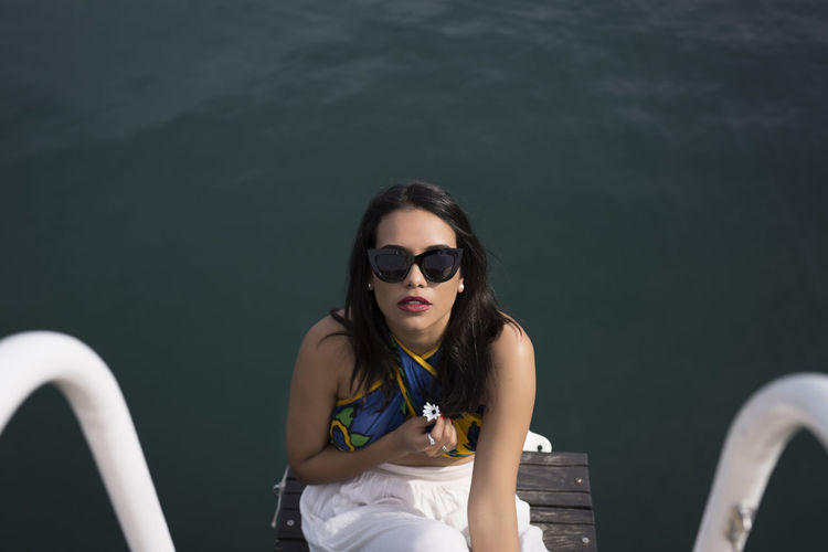 Portrait of young woman wearing sunglasses while swimming in sea