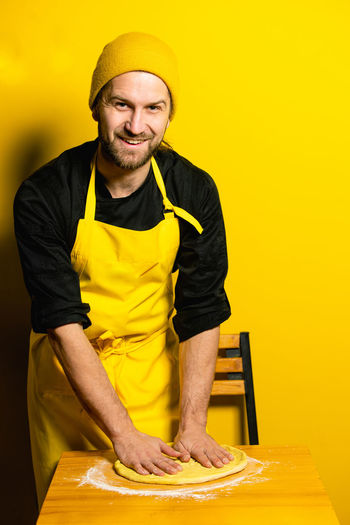 Portrait of chef preparing food against colored background