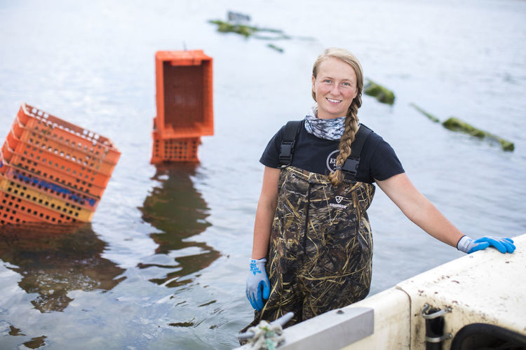 Portrait of female shellfish farmner standing in water